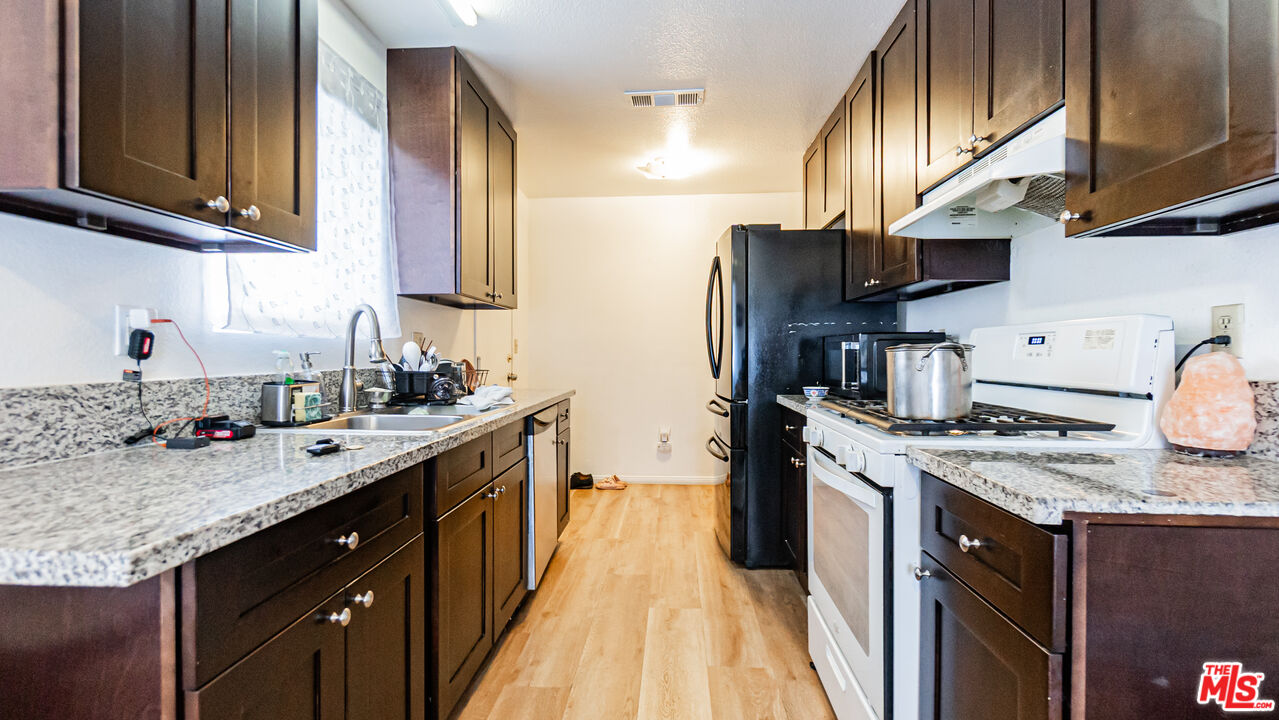 586 San Dimas Street Hemet, CA 92545 - Photo 8 of 30 a kitchen with stainless steel appliances granite countertop a sink stove and refrigerator