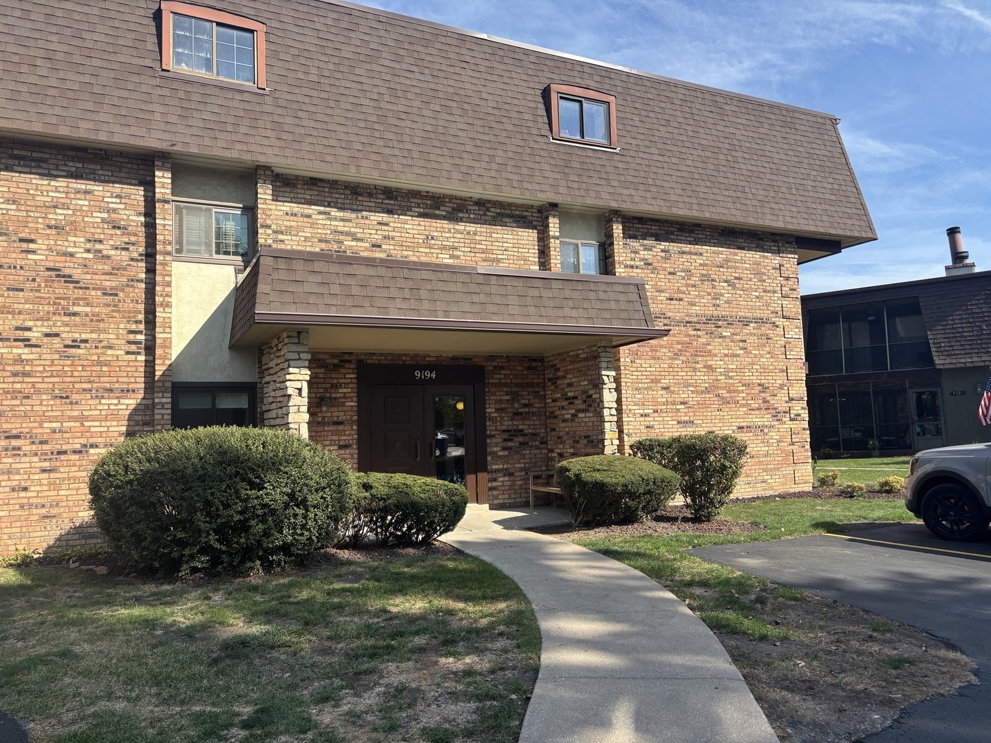 9194 S Road, Unit B Palos Hills, IL 60465 - Photo 2 of 10 a view of a house with a yard plants and a car parked in front of it