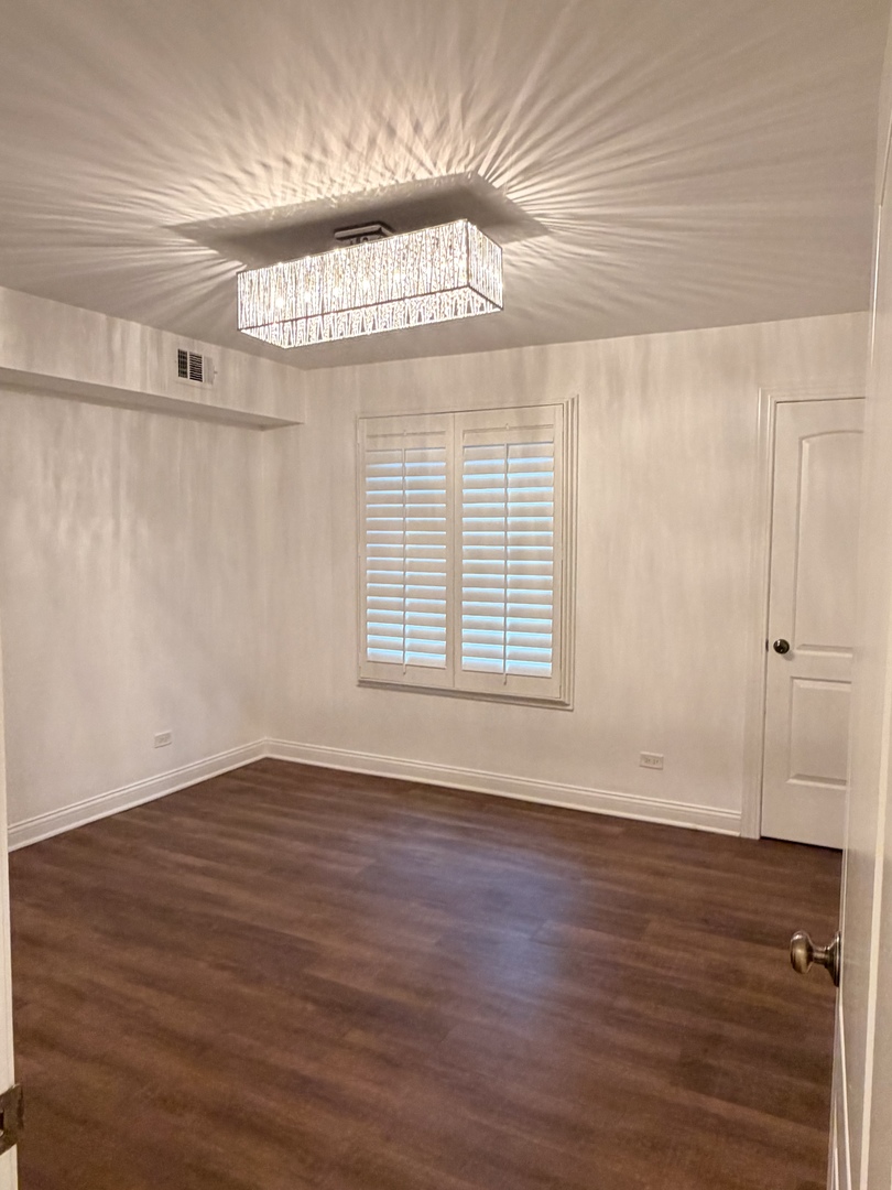 9194 S Road, Unit B Palos Hills, IL 60465 - Photo 6 of 10 a view of an empty room with wooden floor and a window