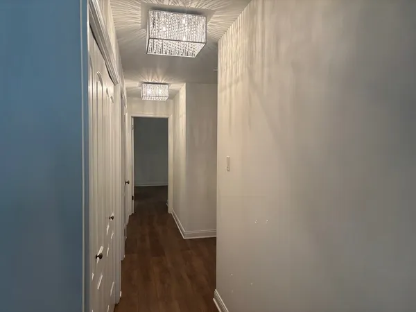a view of a hallway with wooden floor and a chandelier