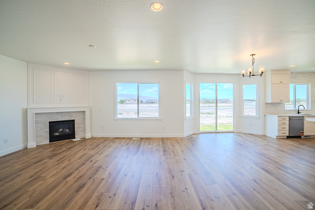 45 North Scarlet Maple Road, Unit 4317 Vineyard, UT 84059 - Photo 8 of 35 Open-concept living area featuring wood-finish flooring, a contemporary fireplace with tile surround, and an integrated kitchen space