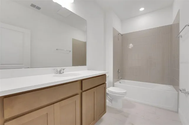 a bathroom with a granite countertop sink a toilet and a bathtub