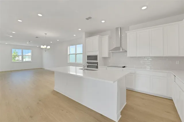 a large white kitchen with kitchen island a sink a stove a refrigerator and white cabinets