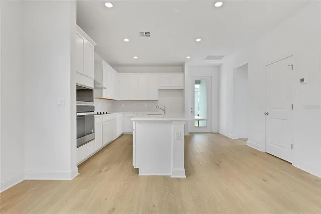 a view of kitchen with kitchen island stainless steel appliances cabinets and wooden floor
