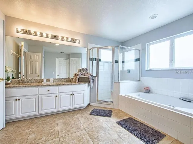 a spacious bathroom with a granite countertop sink mirror and bathtub