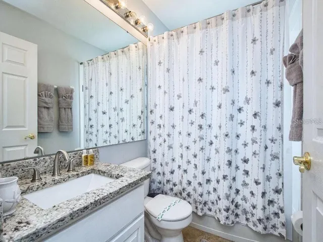 a bathroom with a granite countertop sink a toilet and a mirror