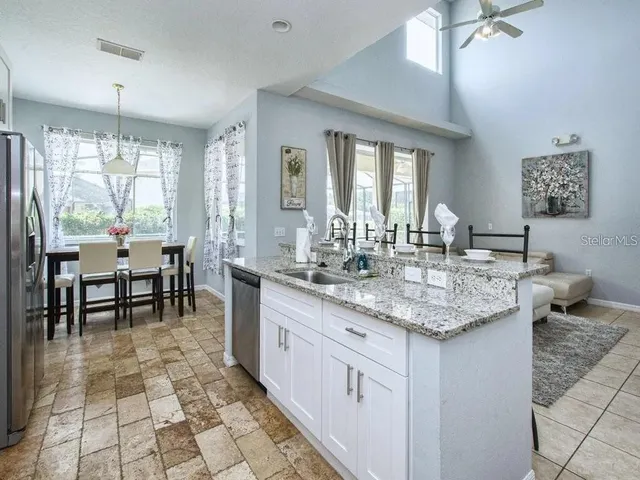 a kitchen with granite countertop a sink a counter top space and stainless steel appliances