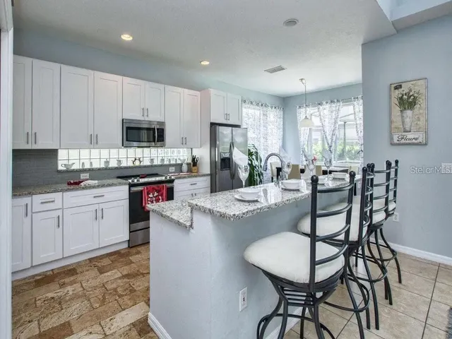 a kitchen with stainless steel appliances granite countertop a stove a sink a microwave a dining table and chairs