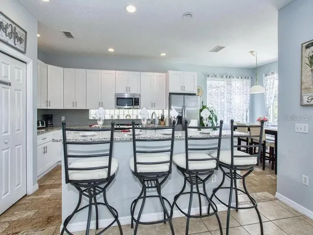 a kitchen with stainless steel appliances a table chairs refrigerator and cabinets