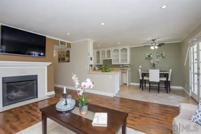 a living room with furniture a flat screen tv and kitchen view