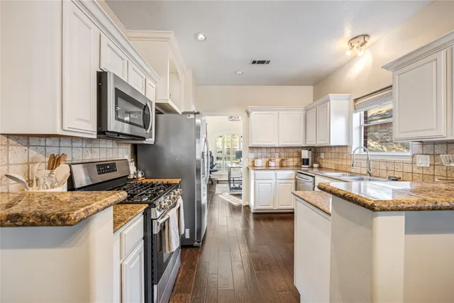 a kitchen with white cabinets and stainless steel appliances