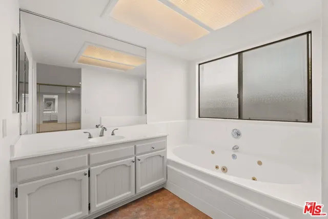 a bathroom with a tub sink and mirror