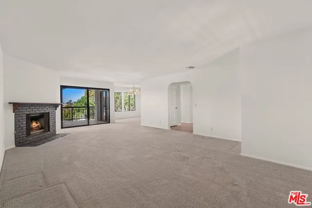 a view of an empty room with a fireplace and a window