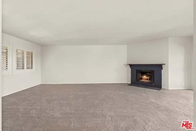 a view of an empty room with a fireplace and a window