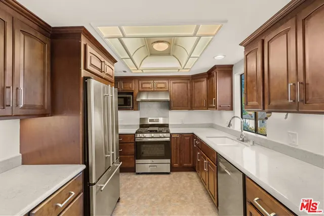 a kitchen with stainless steel appliances granite countertop a sink a stove and a refrigerator