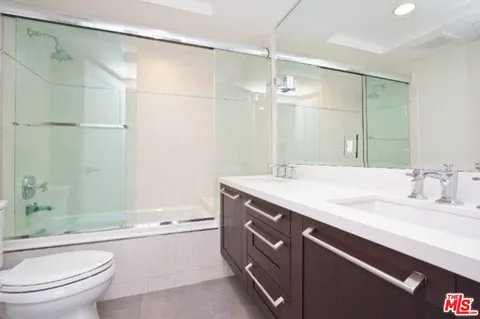 a bathroom with a granite countertop shower sink vanity mirror and toilet