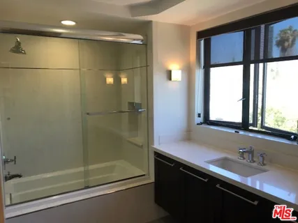 a bathroom with a granite countertop sink a mirror and shower