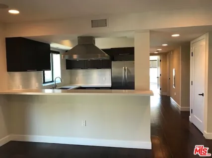 a kitchen with a refrigerator and wooden floor