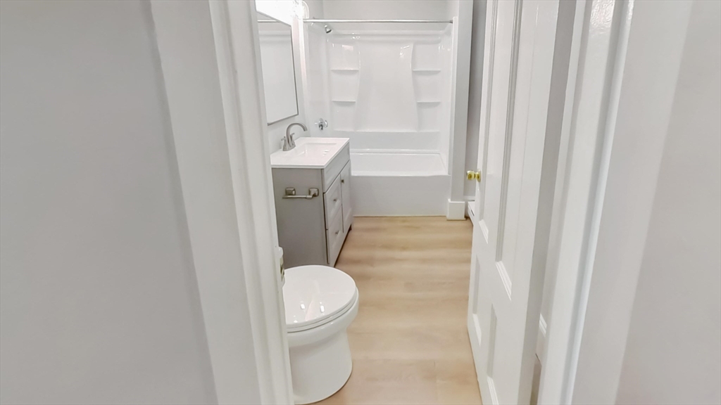44 Guild Street, Unit 1 Boston, MA 02119 - Photo 9 of 9 a bathroom with a granite countertop sink toilet and shower
