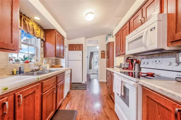 a kitchen with stainless steel appliances granite countertop a stove a sink dishwasher and cabinets with wooden floor