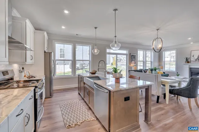 a kitchen with granite countertop a stove a sink a dining table and chairs