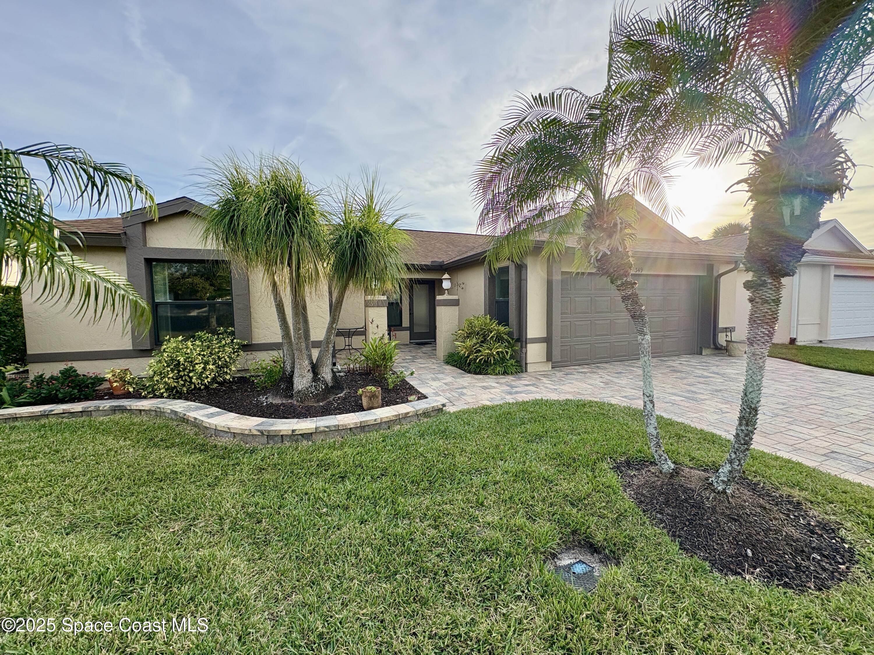 a view of a white house with a big yard and palm trees