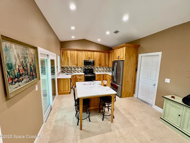 a open kitchen with stainless steel appliances kitchen island granite countertop a refrigerator a stove top oven a sink dishwasher and dining table with wooden floor