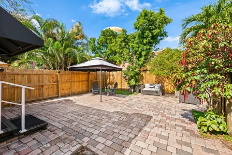 a backyard of a house with table and chairs under an umbrella