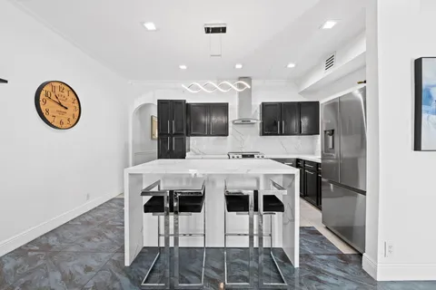 a kitchen with stainless steel appliances kitchen island granite countertop a refrigerator a stove a microwave oven a sink with island and chairs