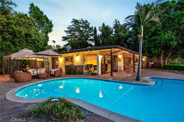 a view of a swimming pool with lawn chairs under an umbrella