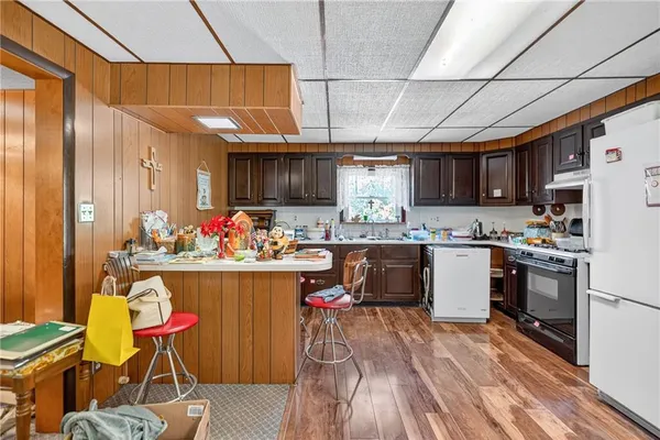 a kitchen with stainless steel appliances kitchen island granite countertop a table chairs in it and wooden floors