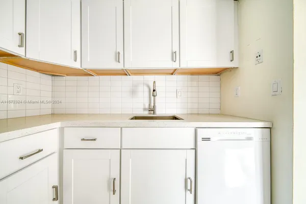a kitchen with granite countertop white cabinets and a sink
