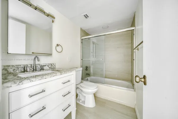 a bathroom with a granite countertop sink toilet mirror vanity and bathtub