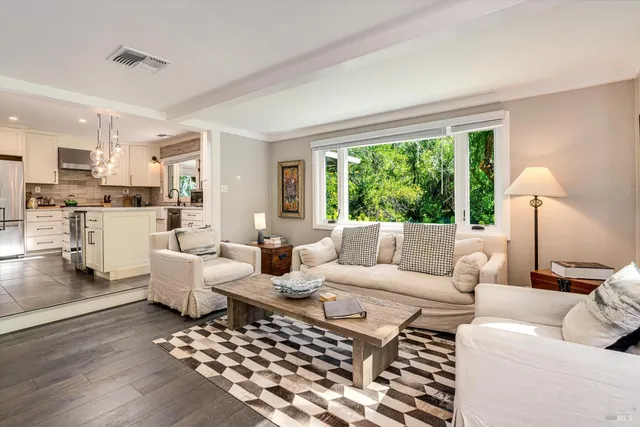 a large kitchen with stainless steel appliances kitchen island granite countertop a refrigerator a sink dishwasher a stove and white cabinets with wooden floor