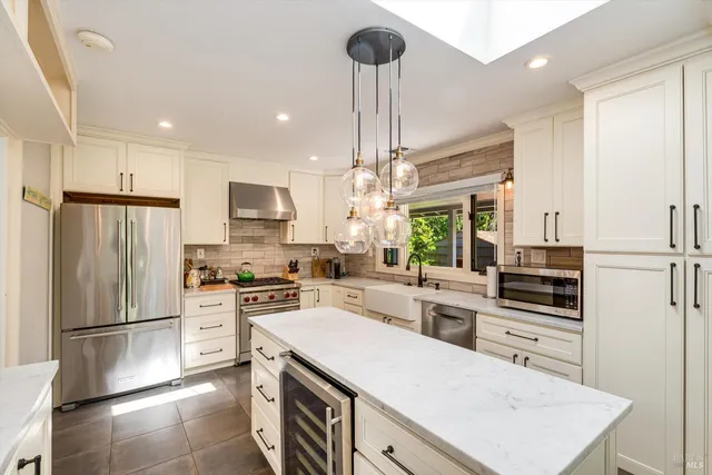a kitchen with kitchen island granite countertop a sink cabinets stainless steel appliances and a counter top