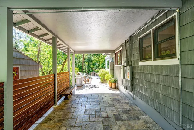 a backyard with table and chairs with potted plants and large trees