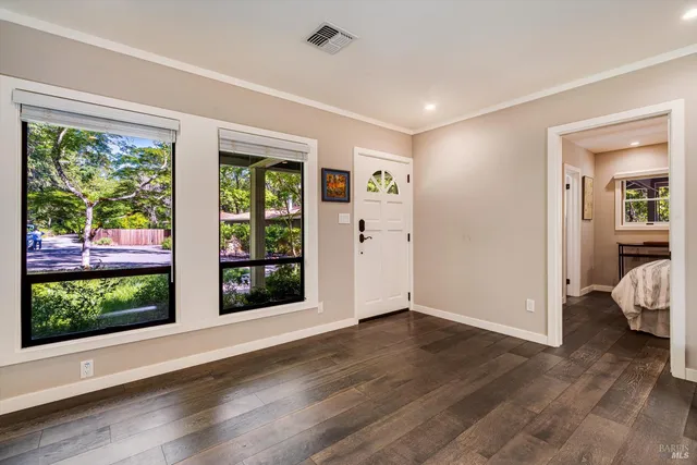a view of an empty room with a window and wooden floor