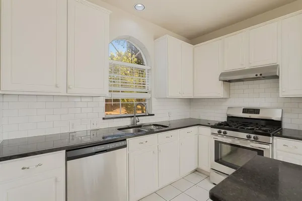 a kitchen with granite countertop a sink cabinets and window