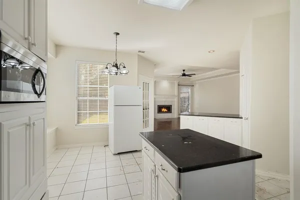 a kitchen with granite countertop white cabinets and refrigerator