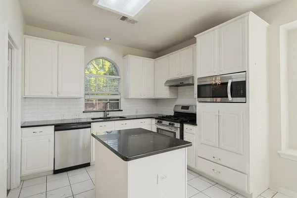 a kitchen with granite countertop white cabinets and white appliances