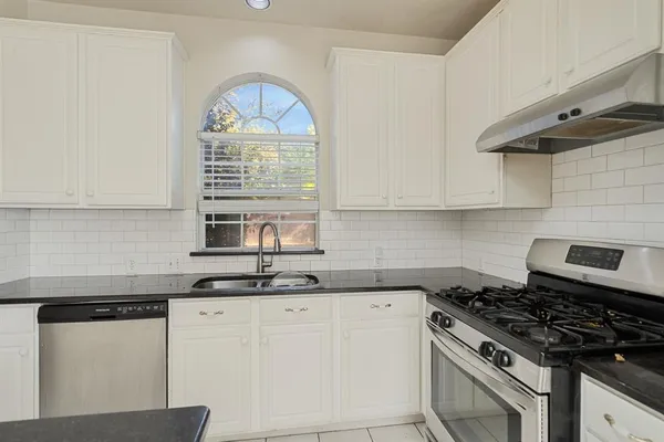 a kitchen with granite countertop a sink a stove and cabinets