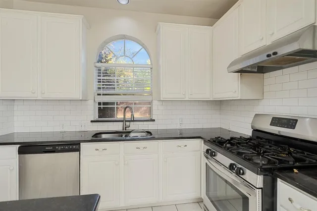 a kitchen with granite countertop a sink a stove and cabinets