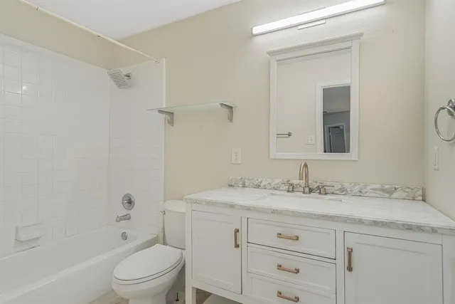 a bathroom with a granite countertop sink toilet vanity granite shower and a mirror
