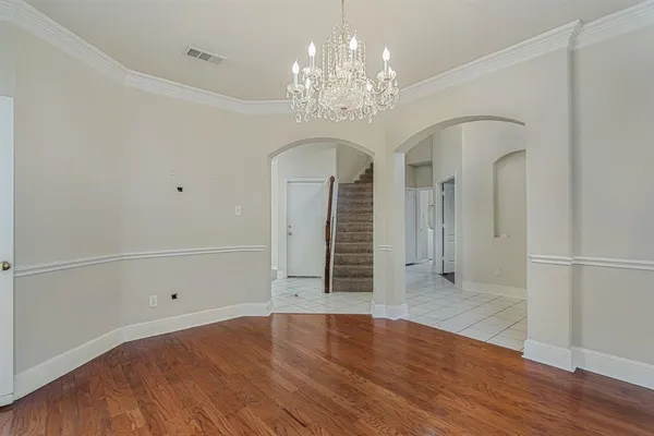 wooden floor in an empty room with a chandelier