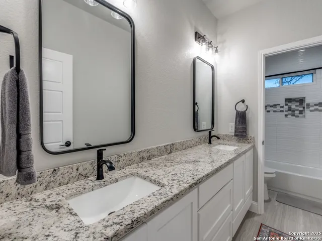 a bathroom with a granite countertop sink and a mirror