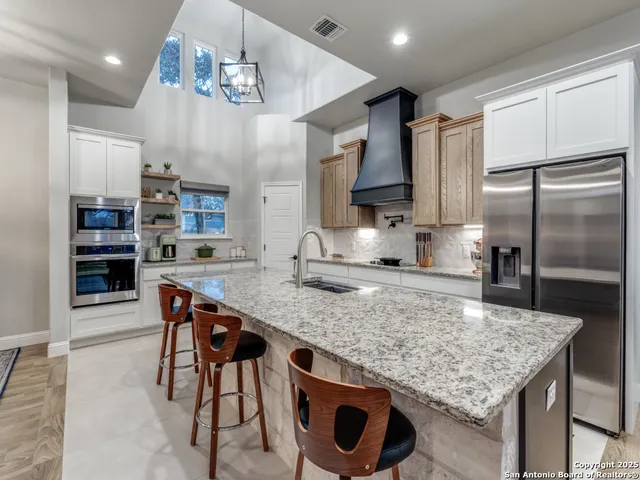 a kitchen with stainless steel appliances granite countertop a kitchen island a stove and a sink