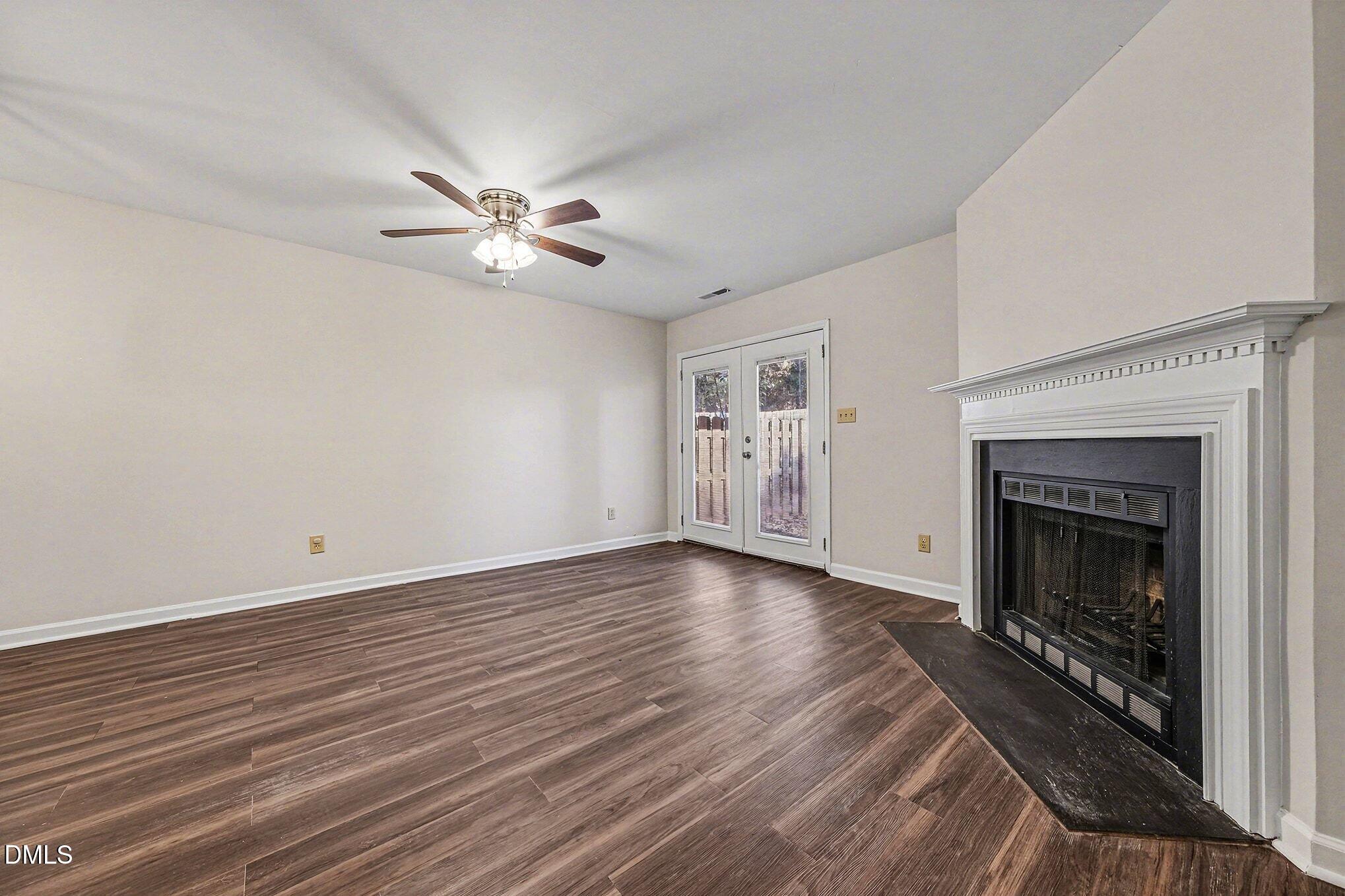 1509 Clermont Road, Unit T27 Durham, NC 27713 - Photo 6 of 26 an empty room with wooden floor a ceiling fan a fireplace and windows