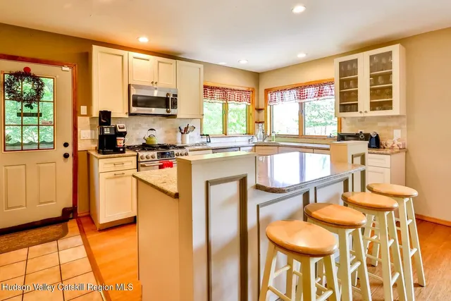 a kitchen with stainless steel appliances granite countertop a stove a sink dishwasher and a refrigerator with wooden floor