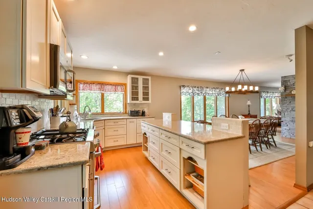 a large white kitchen with a large window and stainless steel appliances