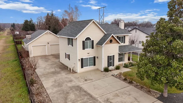 a view of a white house next to a yard with large trees